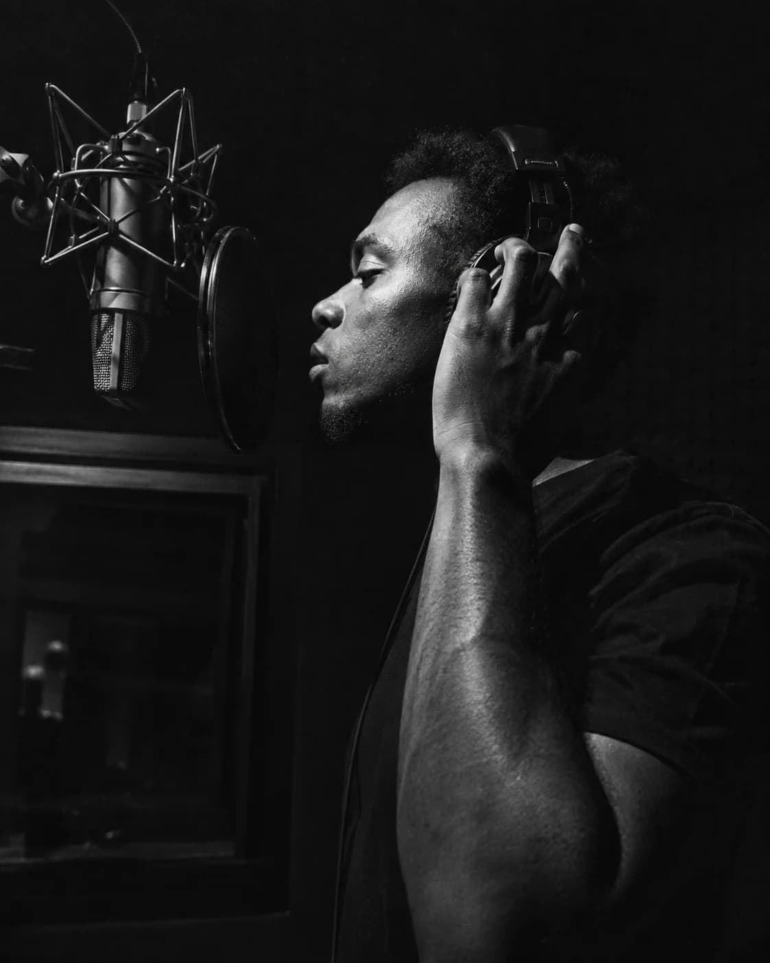 A vocalist in headphones recording at a studio microphone